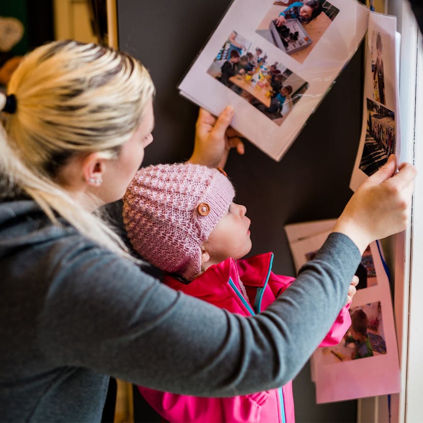 Voksen og barn titter på bilder på en vegg